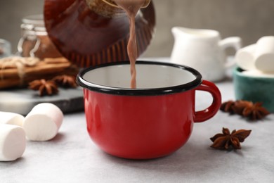 Photo of Pouring tasty hot chocolate into cup at light table, closeup