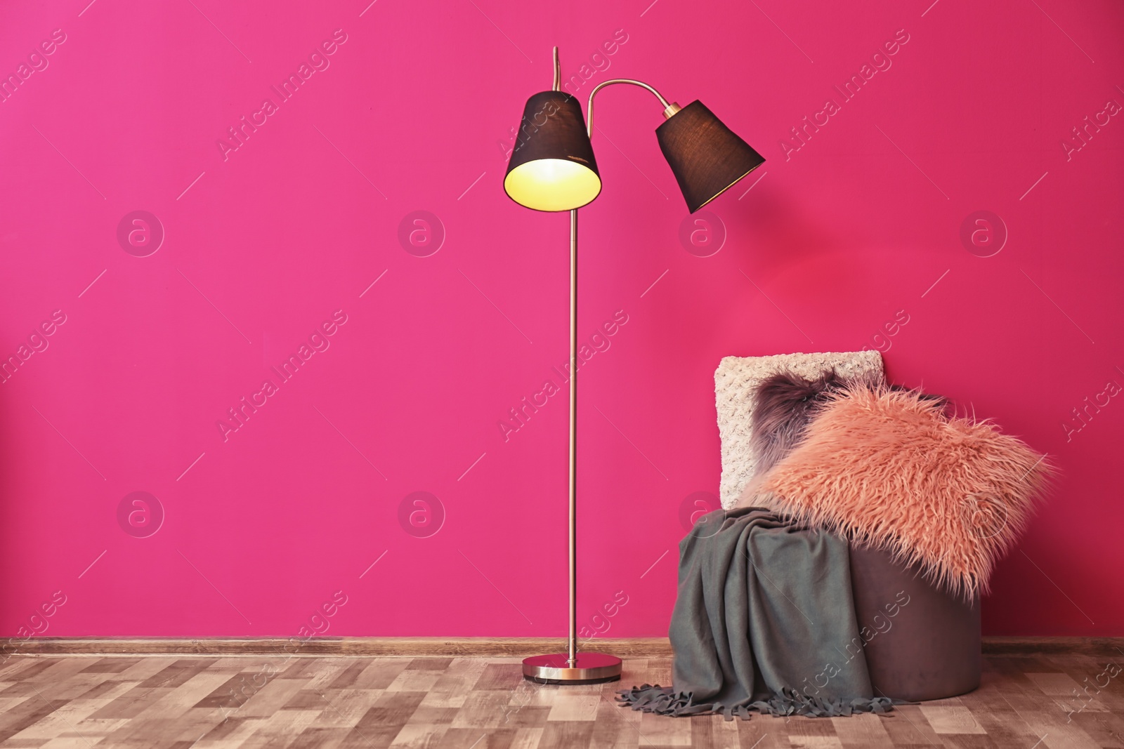 Photo of Ottoman chair with different pillows near color wall in room