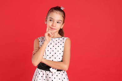Photo of Cute girl with small crown on red background. Little princess