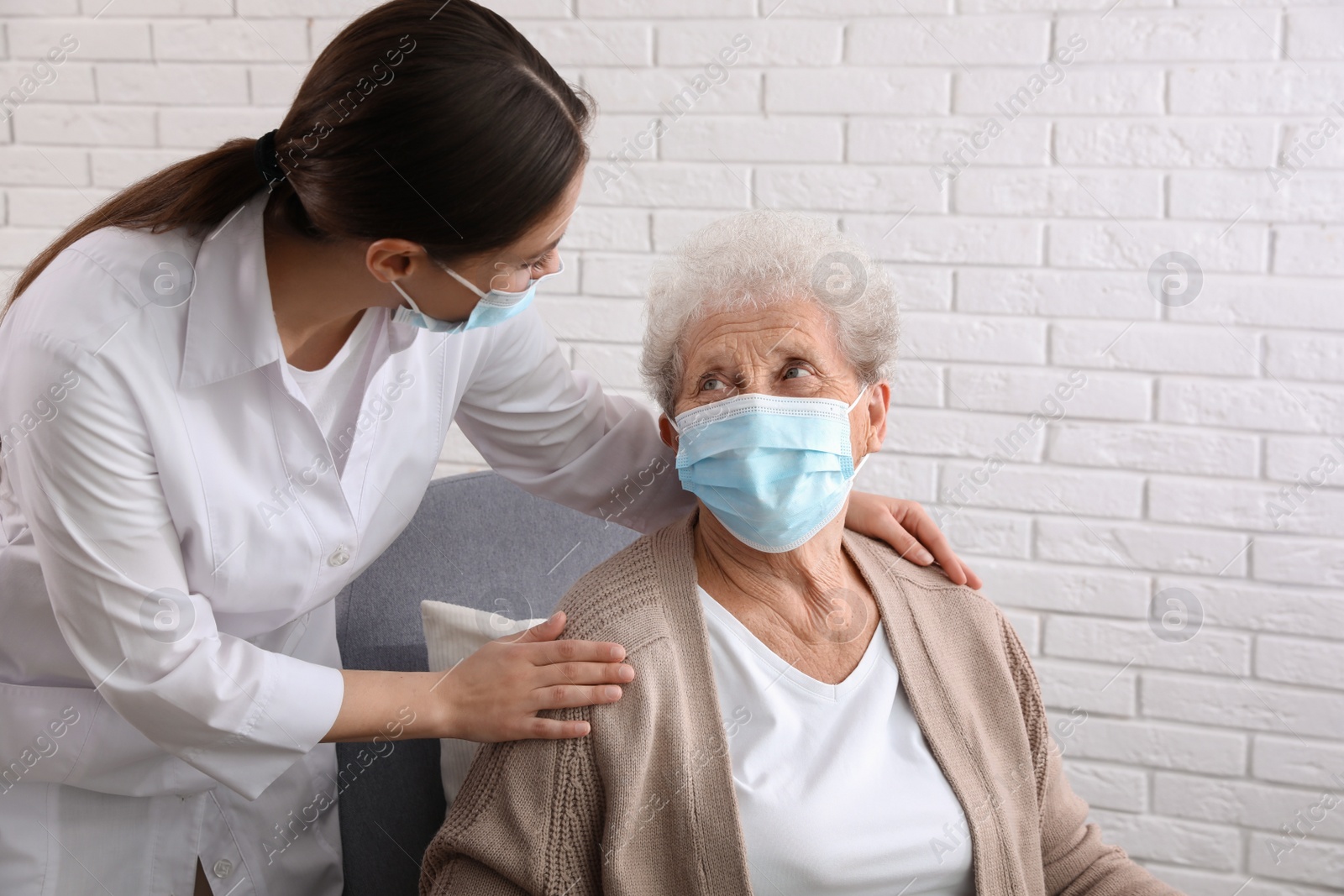 Photo of Doctor taking care of senior woman in protective mask at nursing home