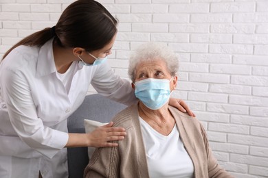 Photo of Doctor taking care of senior woman in protective mask at nursing home