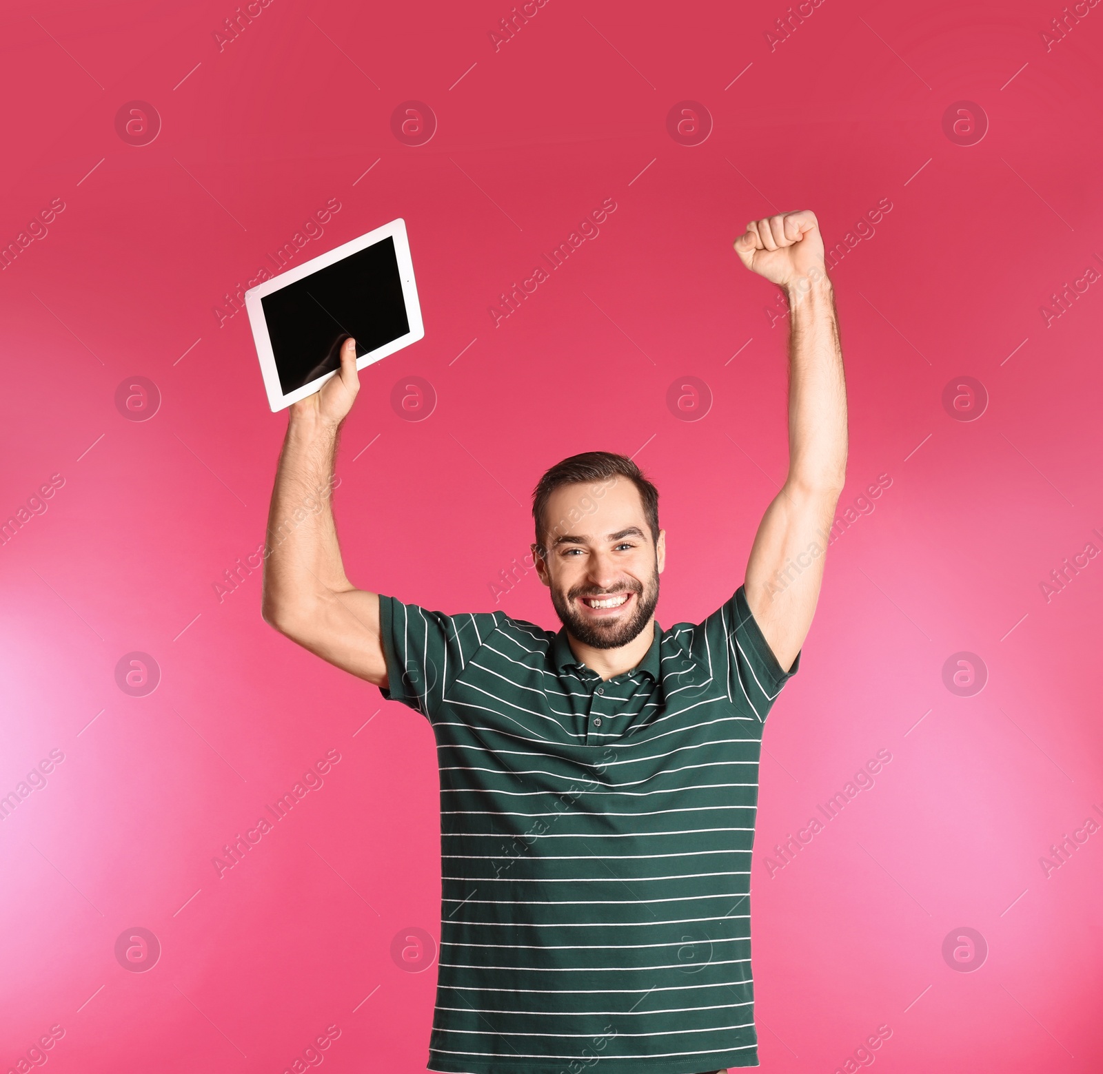 Photo of Emotional young man with tablet celebrating victory on color background