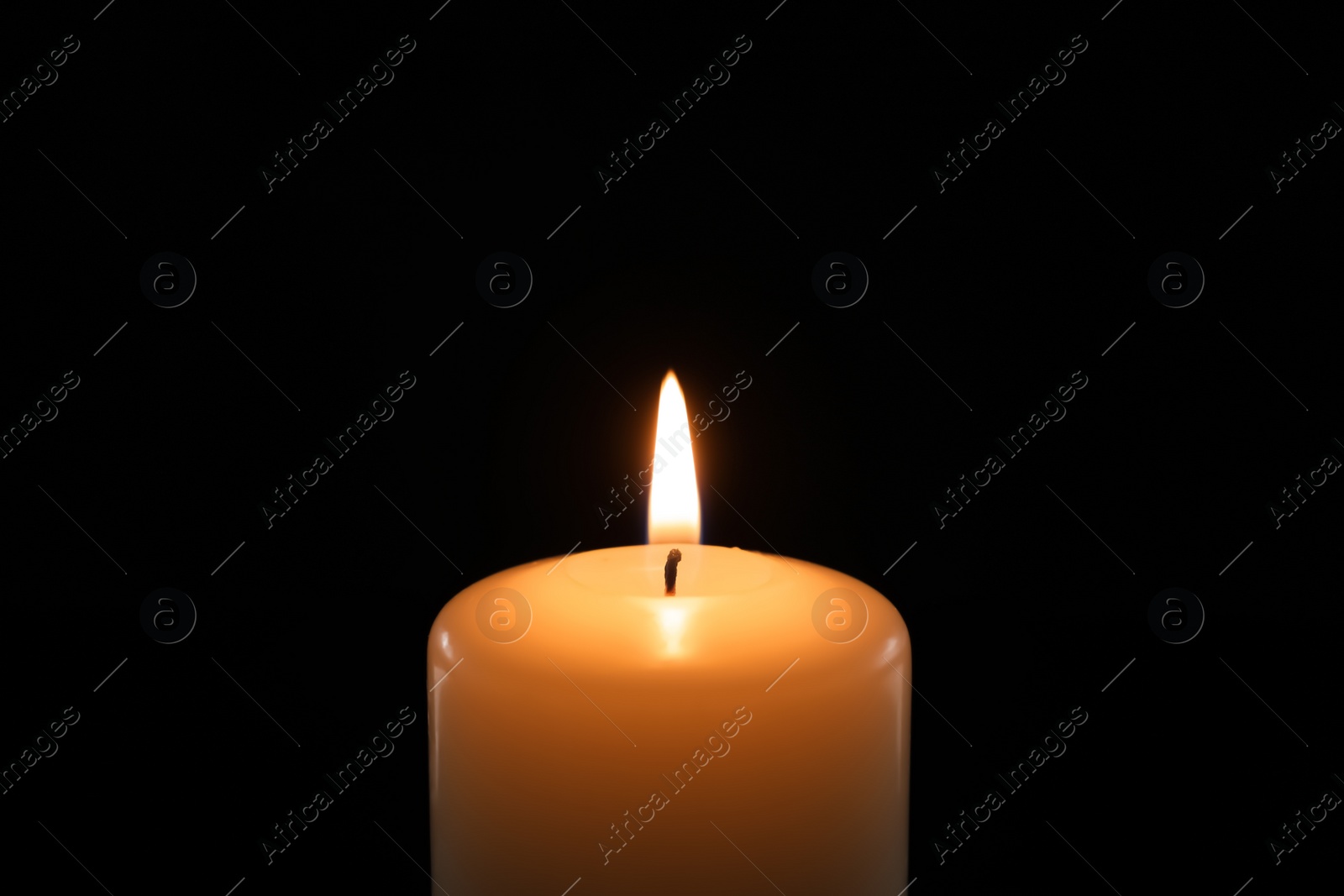 Photo of Wax candle burning on black background, closeup