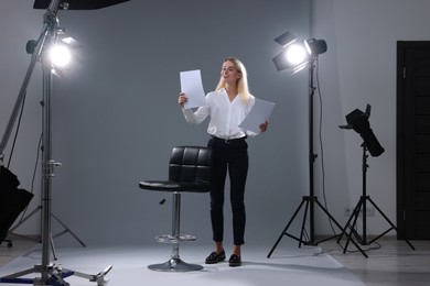 Photo of Casting call. Emotional woman performing against grey background in studio