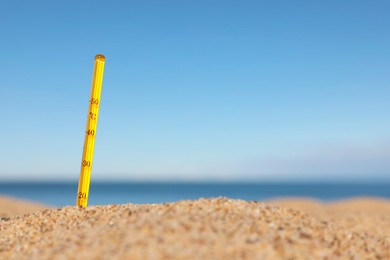 Photo of Weather thermometer in sand near sea, space for text