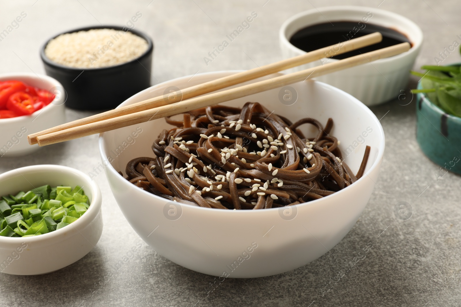 Photo of Tasty buckwheat noodles (soba) with sesame served on light grey table