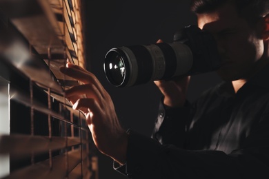 Photo of Private detective with camera spying near window indoors