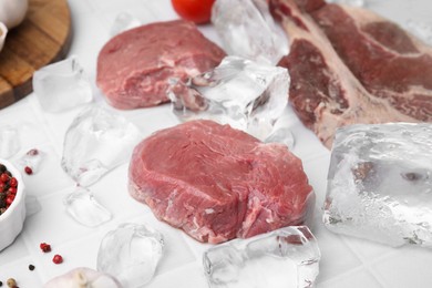 Photo of Fresh raw cut beef and ice cubes on white table, closeup