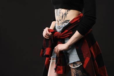 Photo of Woman with cool tattoos on black background, closeup. Space for text