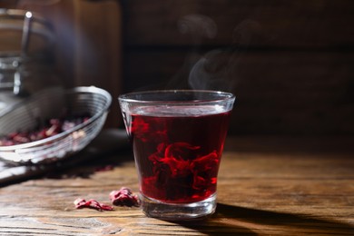 Photo of Delicious hibiscus tea in glass on wooden table, closeup