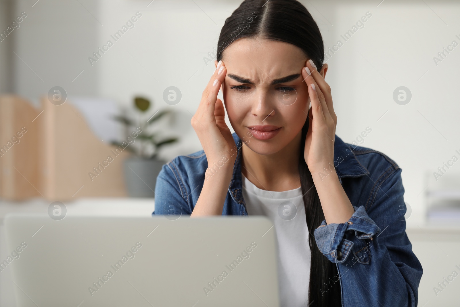 Photo of Woman suffering from headache at workplace in office