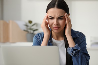 Woman suffering from headache at workplace in office