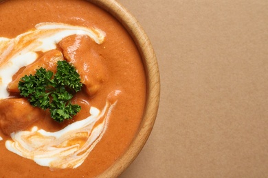 Bowl of delicious butter chicken on color background, top view with space for text. Traditional indian Murgh Makhani