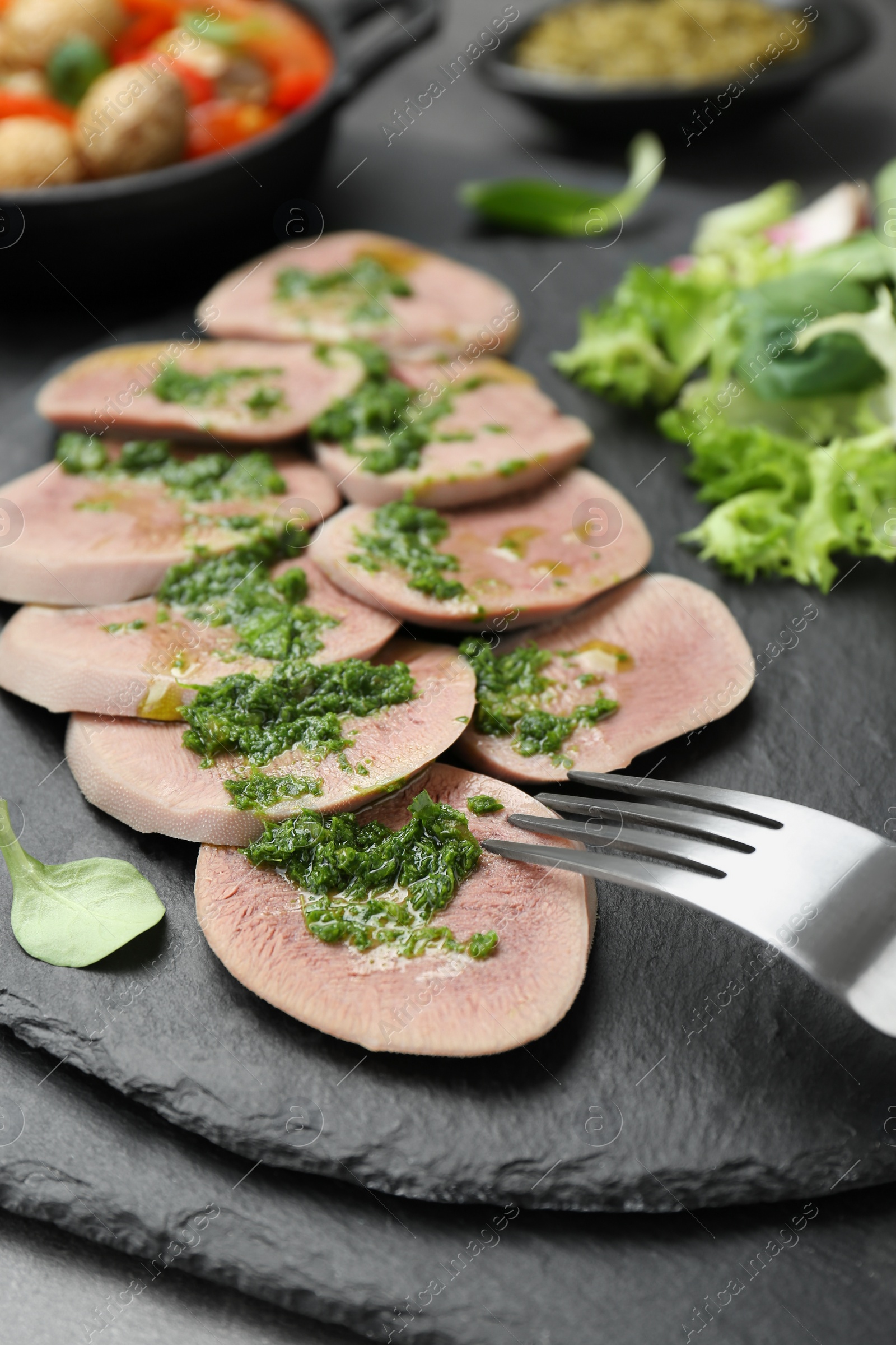 Photo of Tasty beef tongue pieces and salsa verde on grey table, closeup