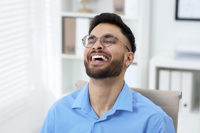 Photo of Portrait of handsome young man laughing in office