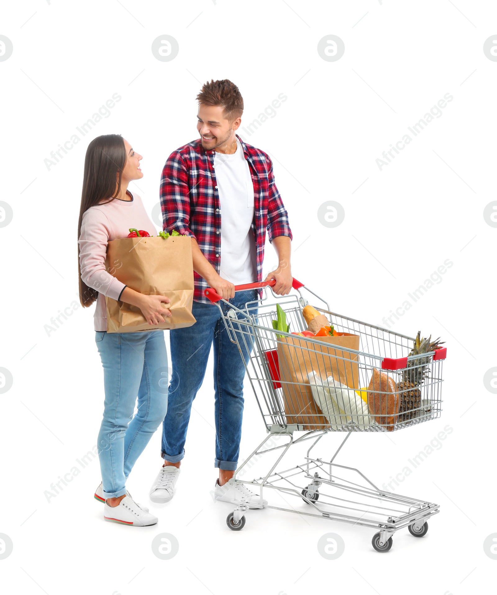 Photo of Young couple with full shopping cart and paper bags on white background