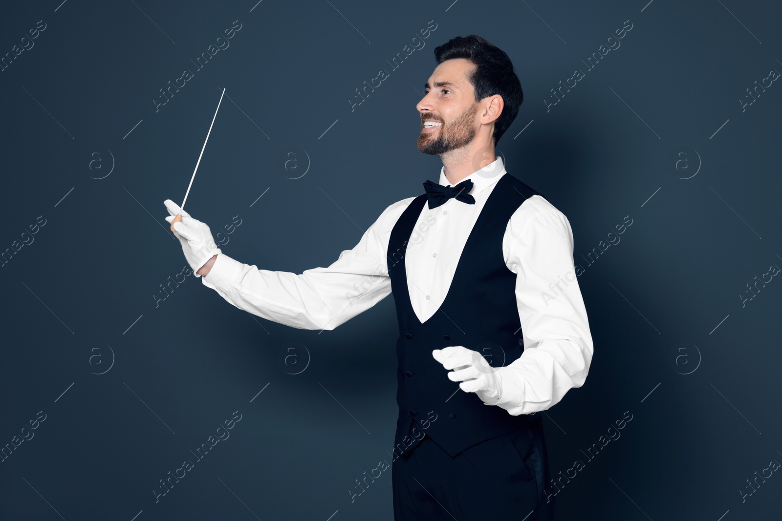 Photo of Happy professional conductor with baton on grey background