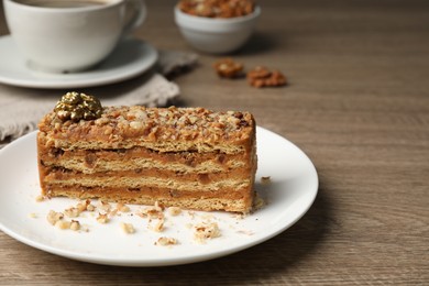 Plate with piece of delicious layered honey cake on wooden table, closeup. Space for text