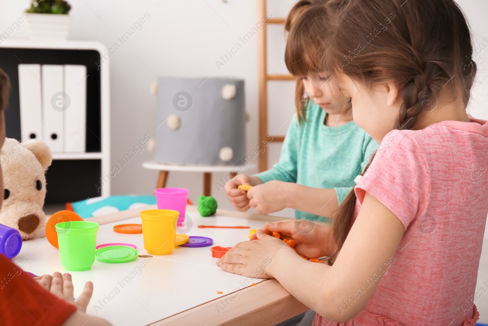 Photo of Cute little children using play dough at table indoors