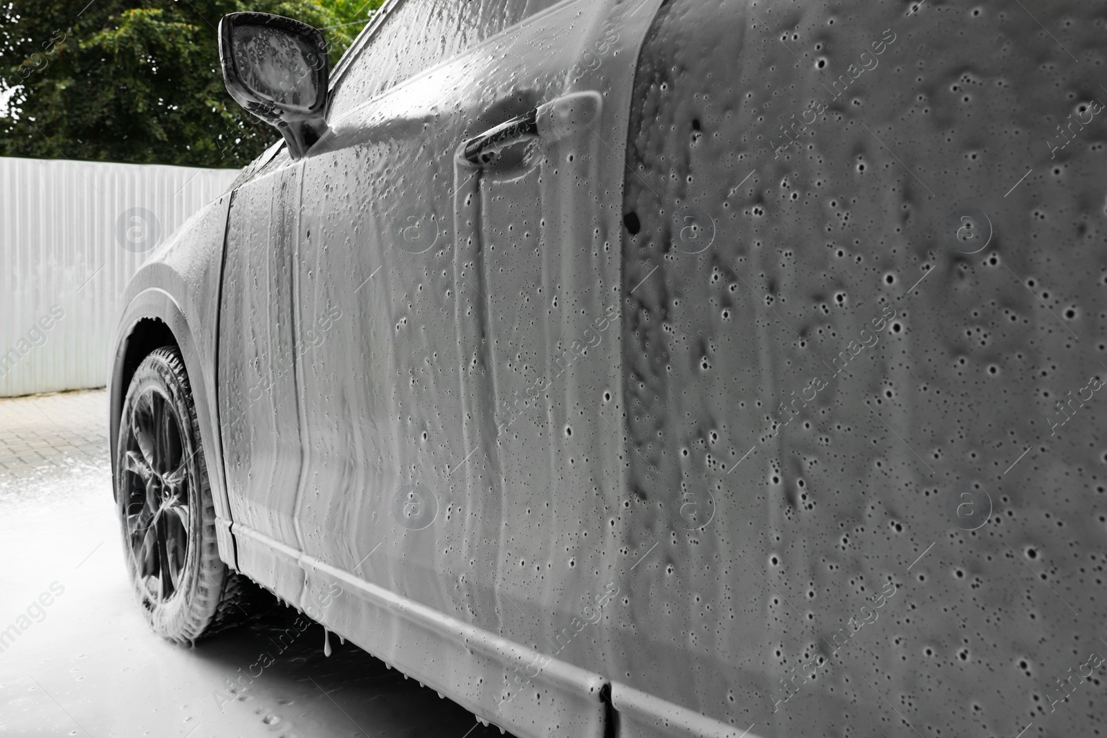 Photo of Auto with cleaning foam at car wash, closeup