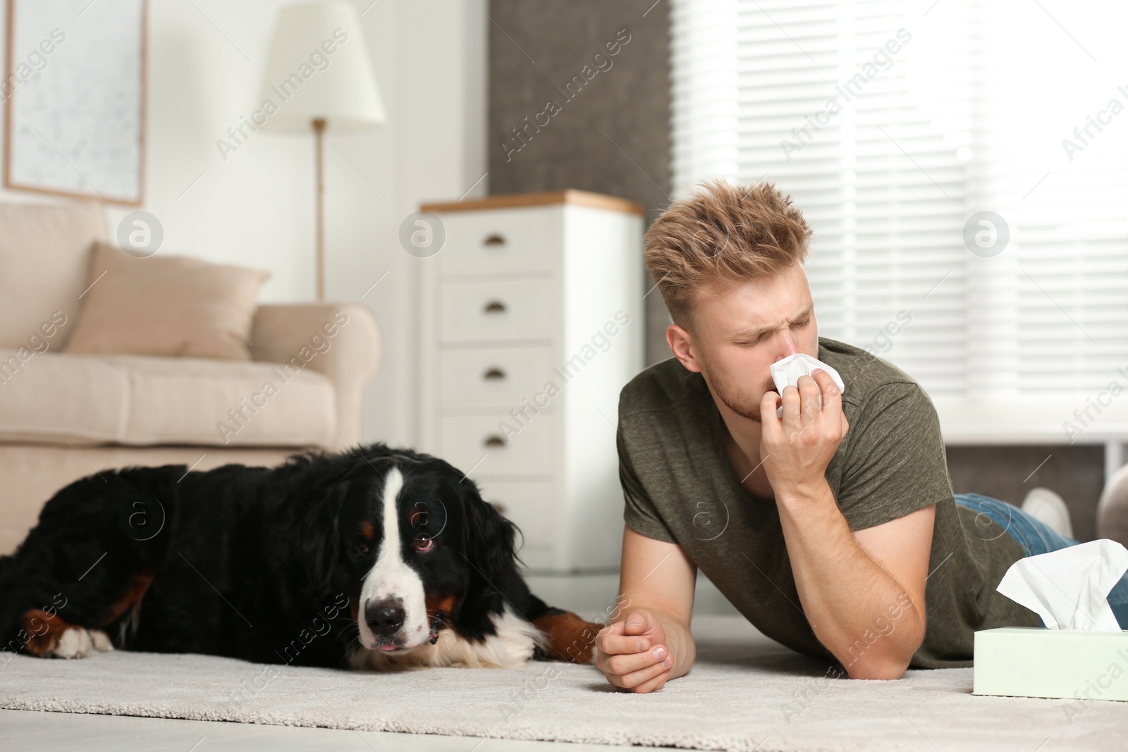 Photo of Young man suffering from fur allergy at home