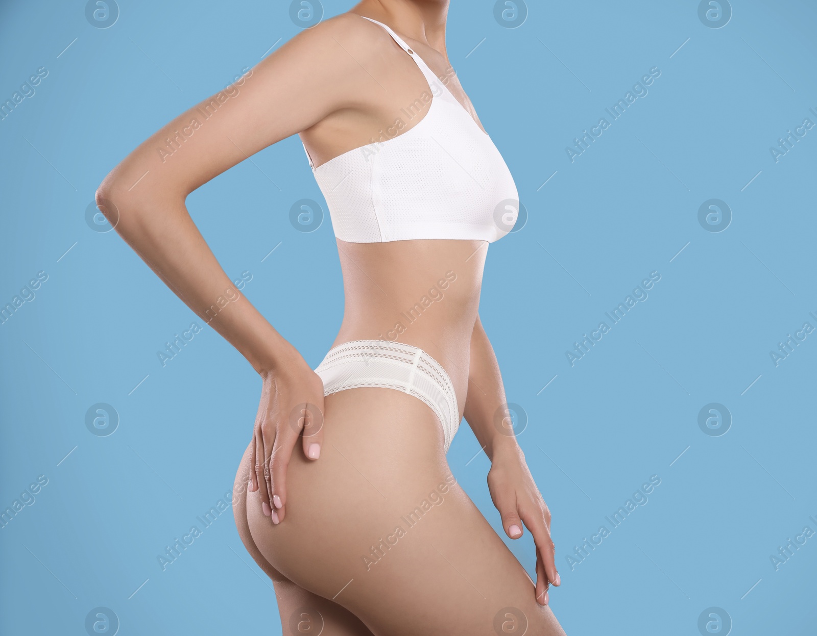 Photo of Closeup view of slim woman in underwear on light blue background, space for text. Cellulite problem concept