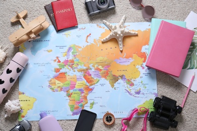 Photo of World map and travel accessories on floor, flat lay. Planning summer vacation trip