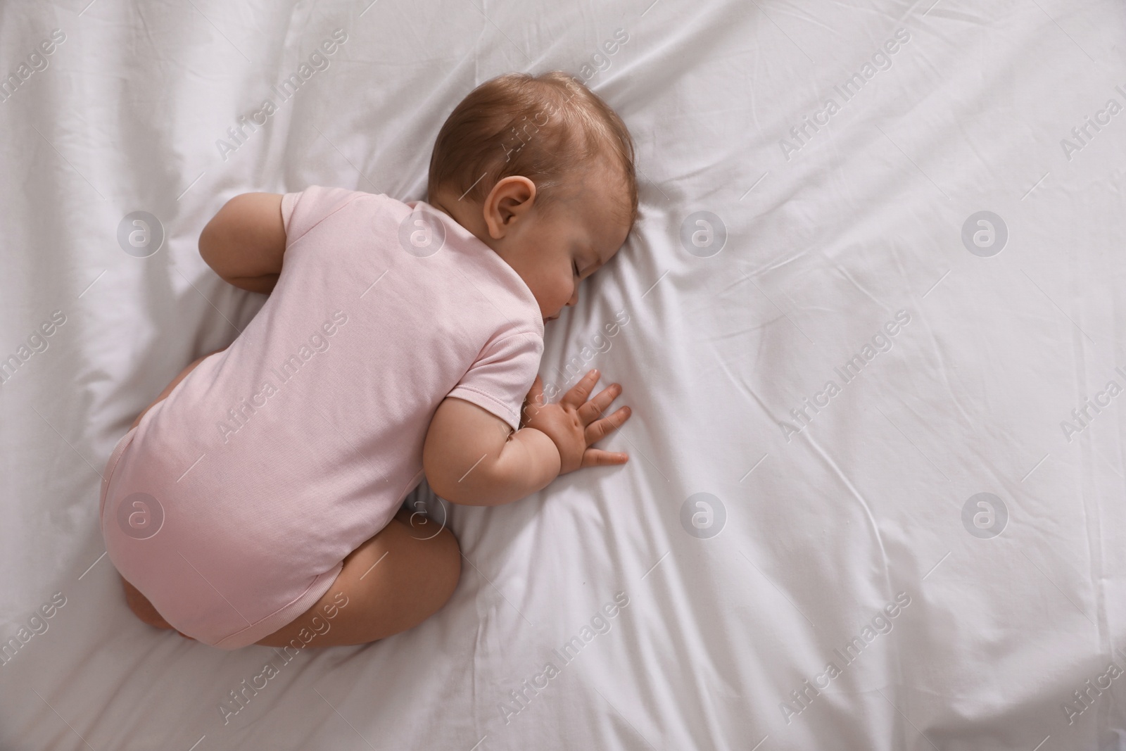 Photo of Adorable little baby sleeping on bed, top view. Space for text