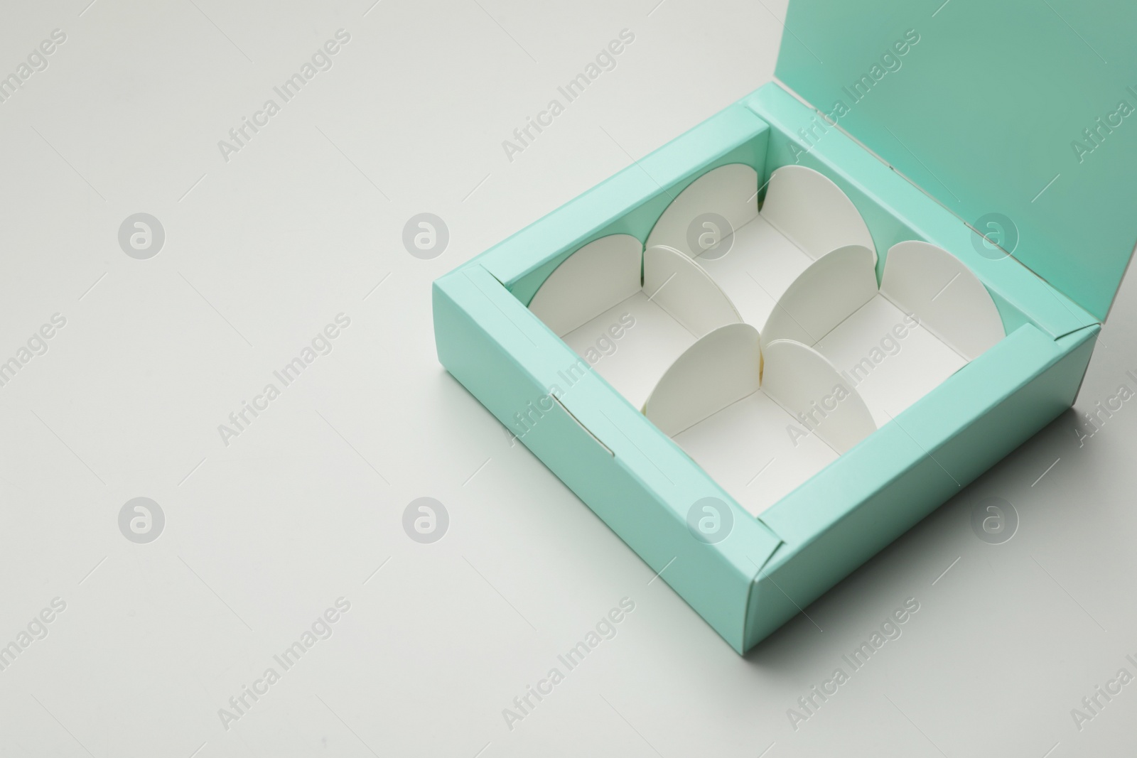 Photo of Empty turquoise candy box on light grey background, space for text
