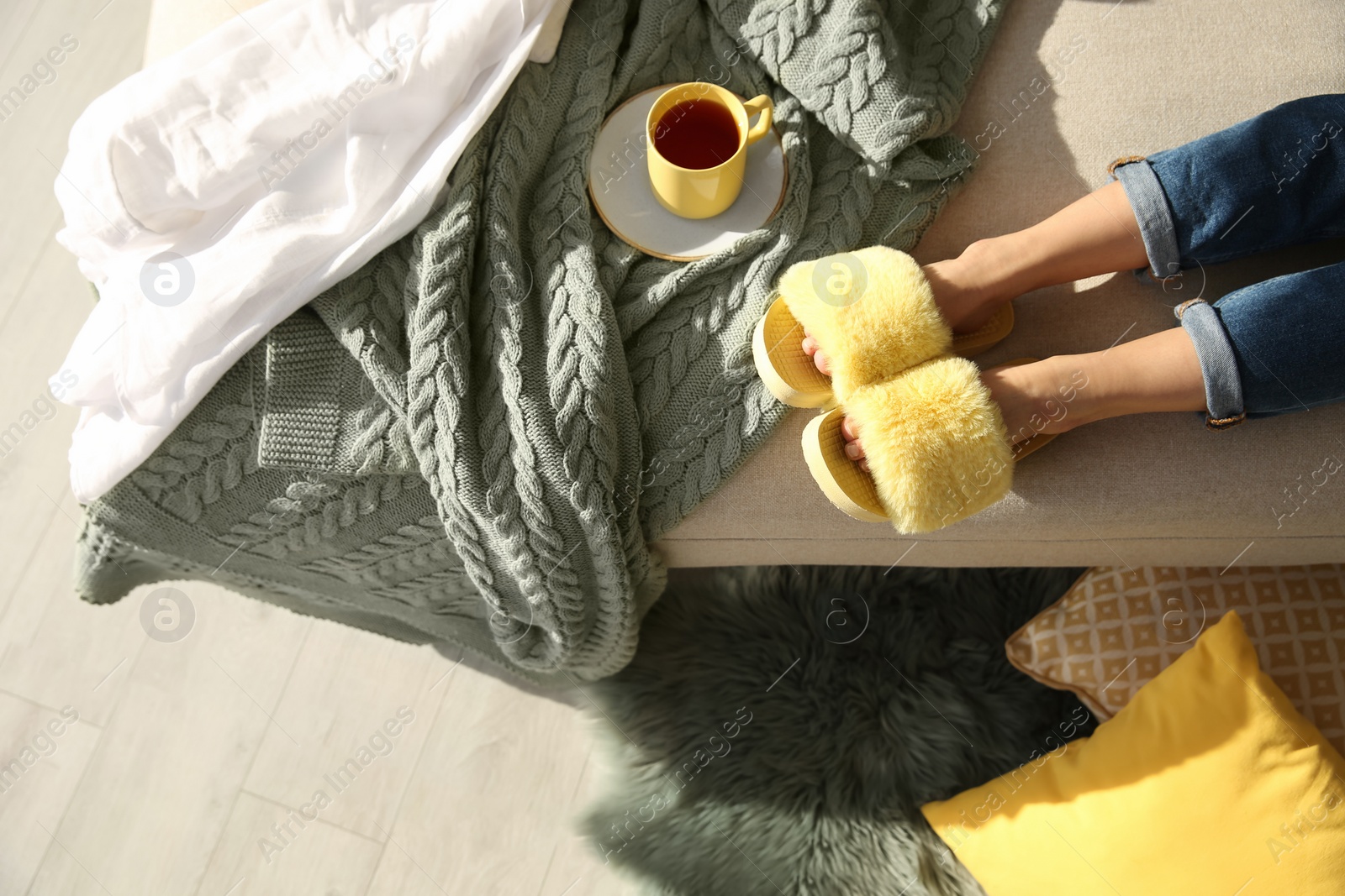 Photo of Woman with cup of tea wearing soft comfortable slippers at home, top view