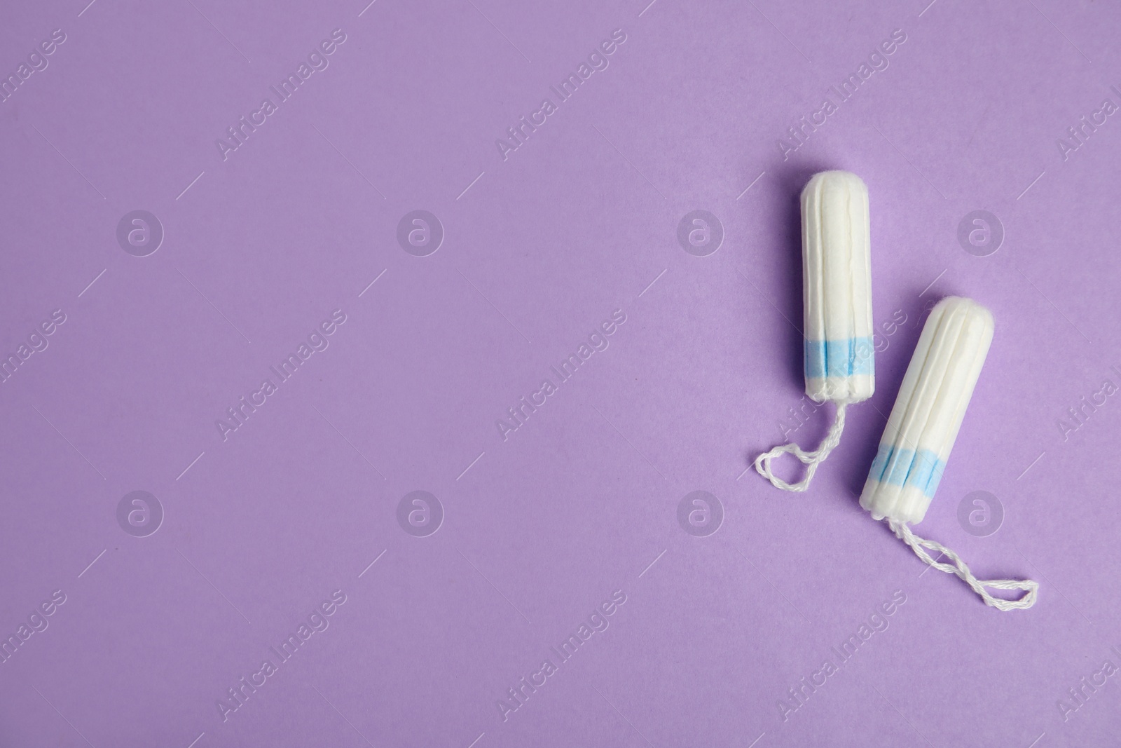 Photo of Tampons on lilac background, flat lay. Space for text