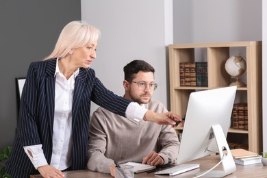 Photo of Boss discussing work issues with employee and pointing at computer in office