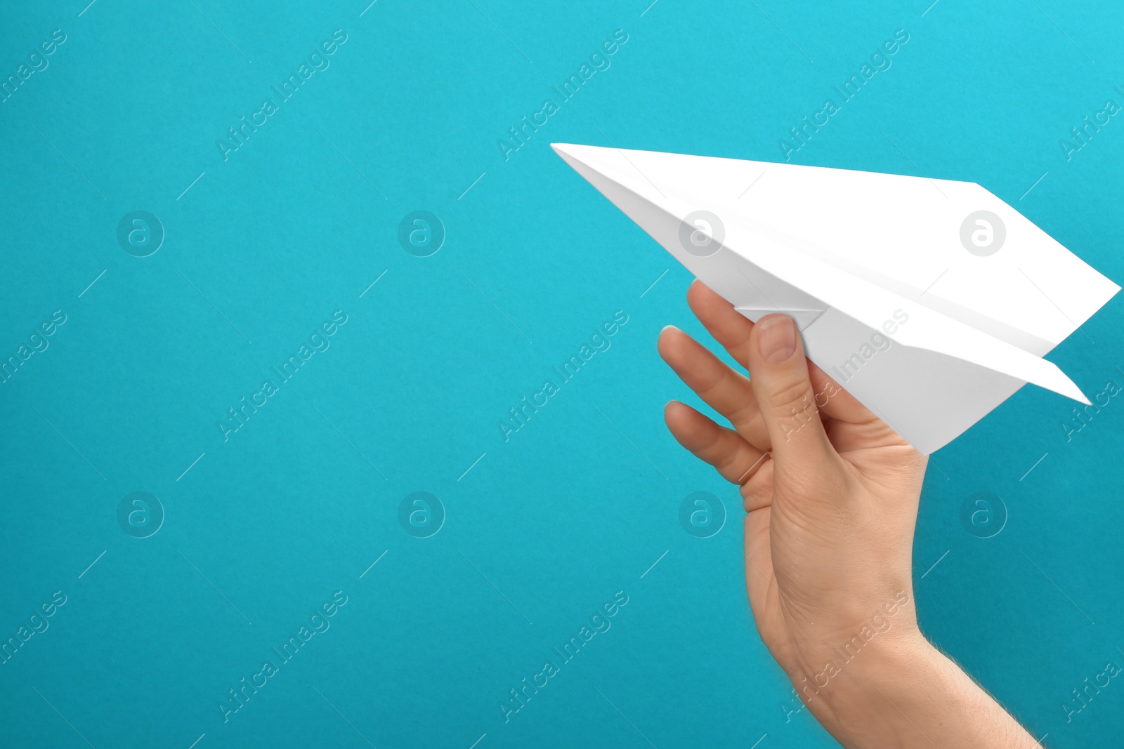 Photo of Woman holding paper plane on light blue background, closeup. Space for text