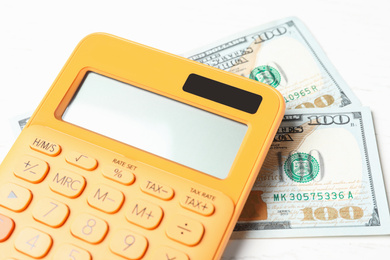 Photo of Calculator and money on white wooden table, closeup. Tax accounting