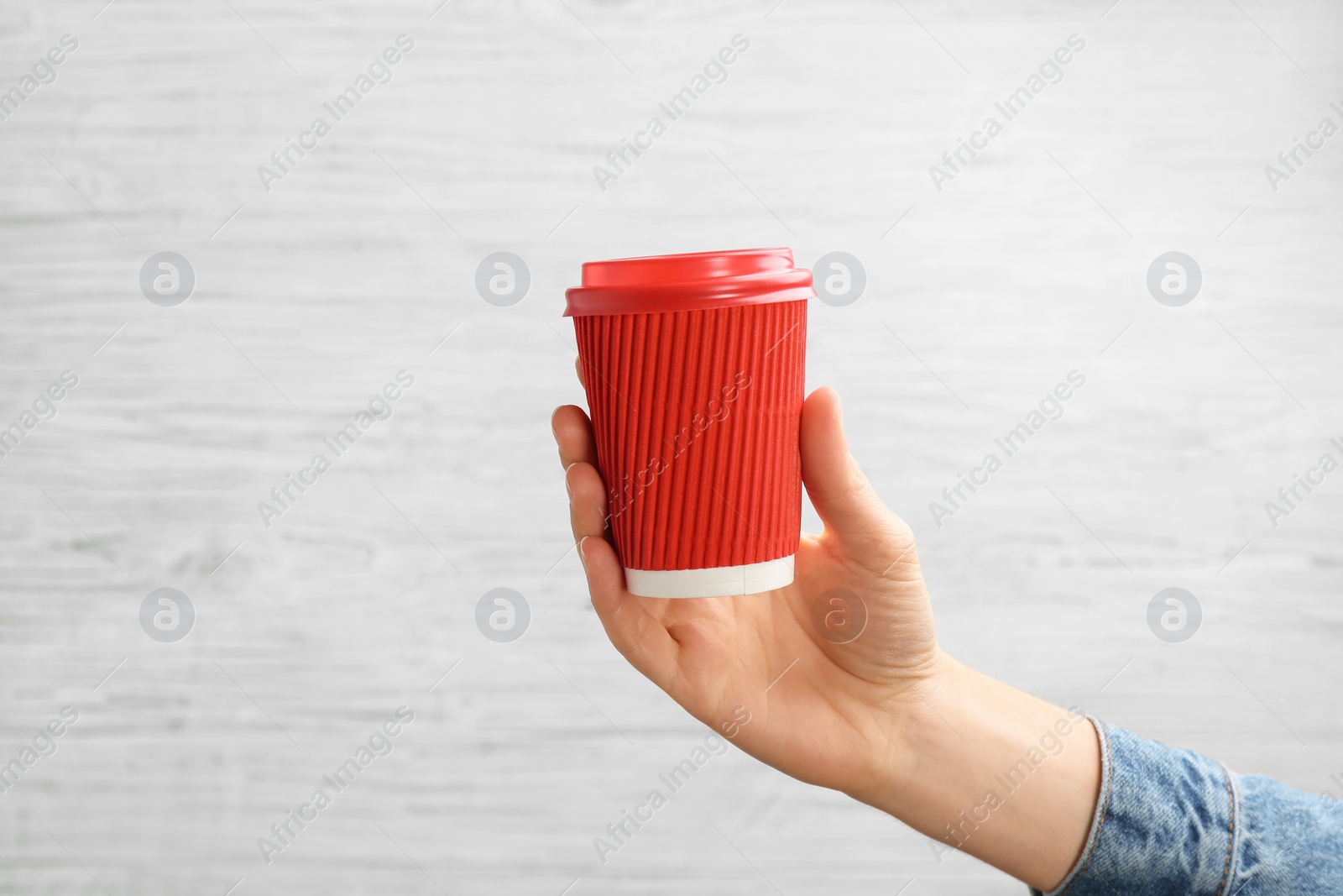 Photo of Woman holding takeaway paper coffee cup on light background