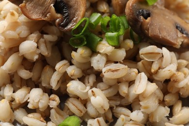 Photo of Delicious pearl barley with onion and mushrooms as background, closeup