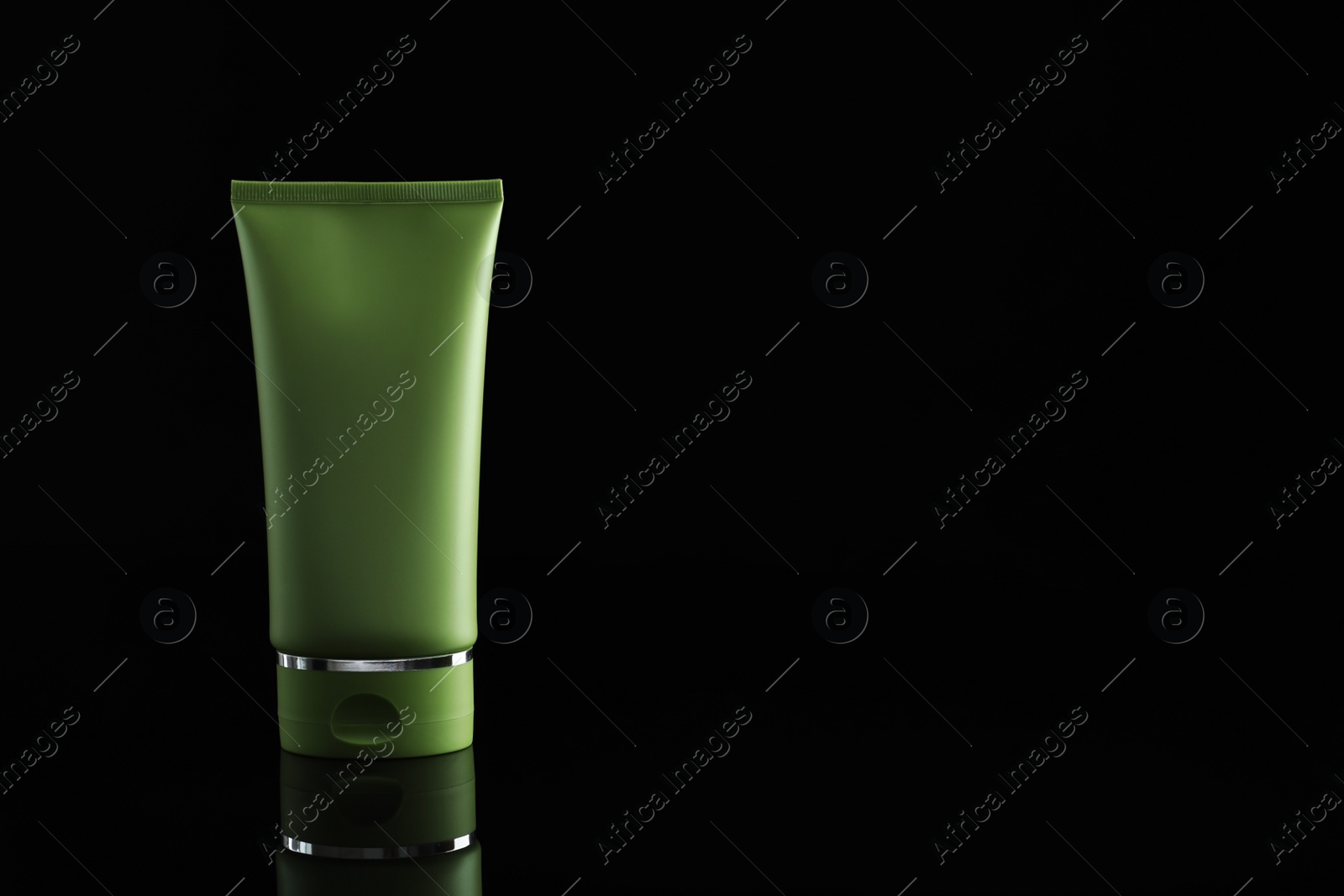 Photo of Tube of cosmetic product on black background, space for text