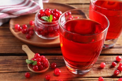 Tasty cranberry juice in glasses and fresh berries on wooden table, closeup