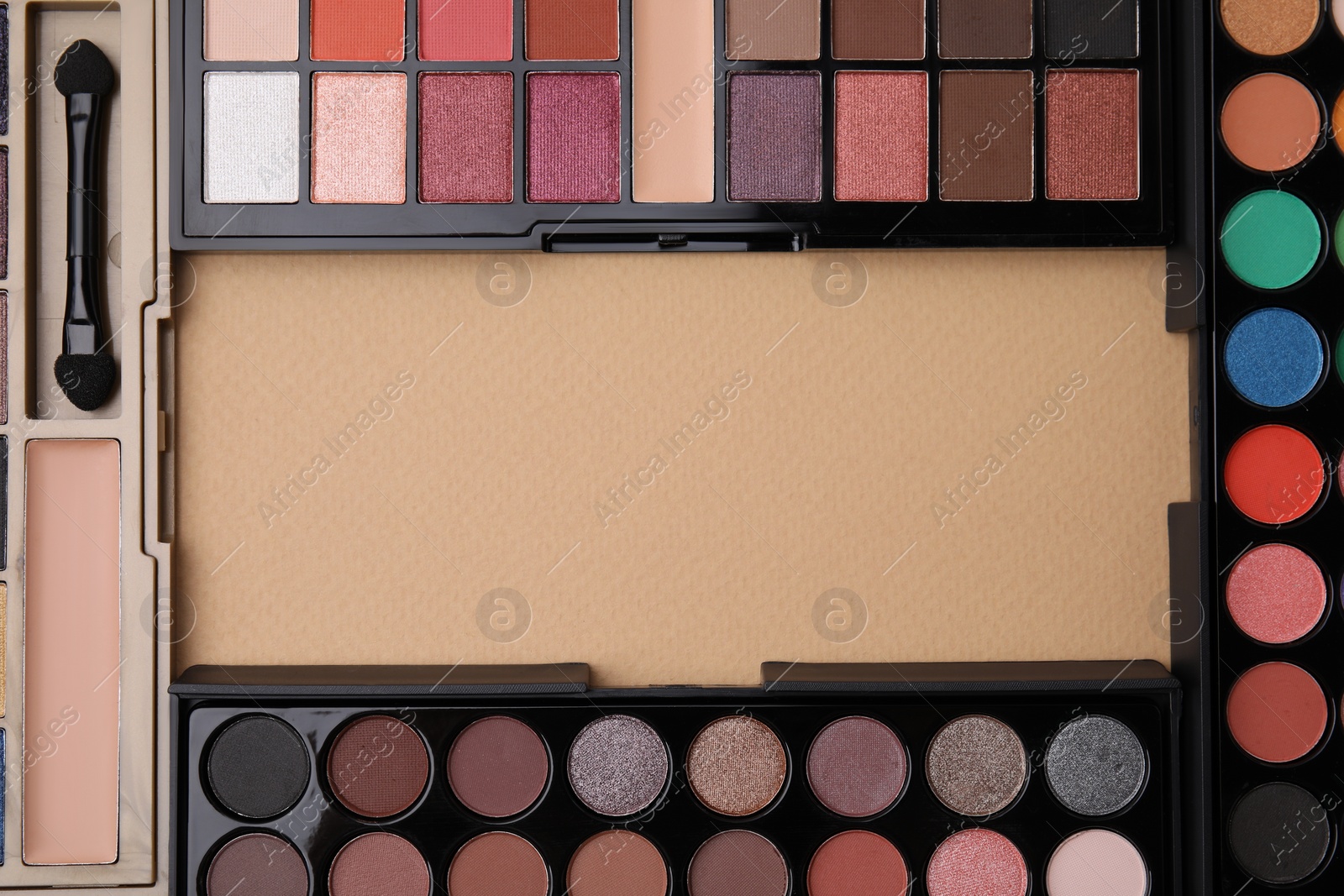 Photo of Frame made of beautiful eye shadow palettes on beige background, flat lay. Space for text