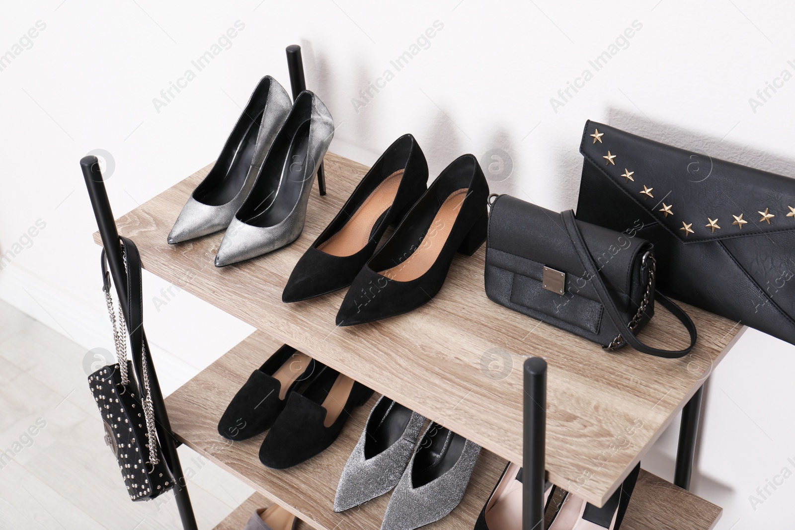 Photo of Shelving unit with stylish shoes and purses near white wall. Element of dressing room interior