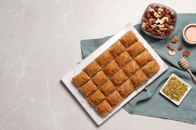 Photo of Delicious sweet baklava with ingredients on light grey marble table, flat lay. Space for text