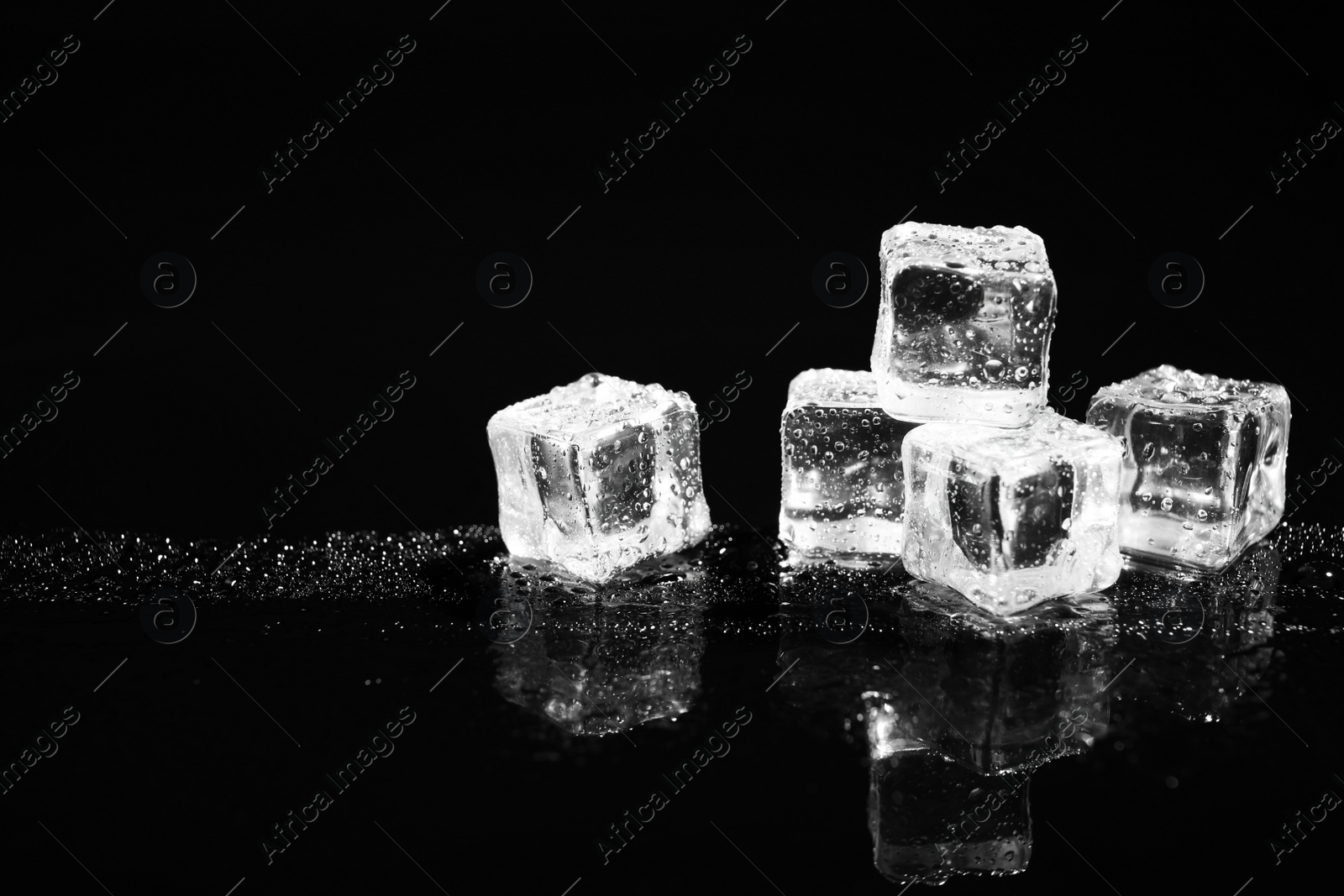 Photo of Pile of crystal clear ice cubes on black background. Space for text