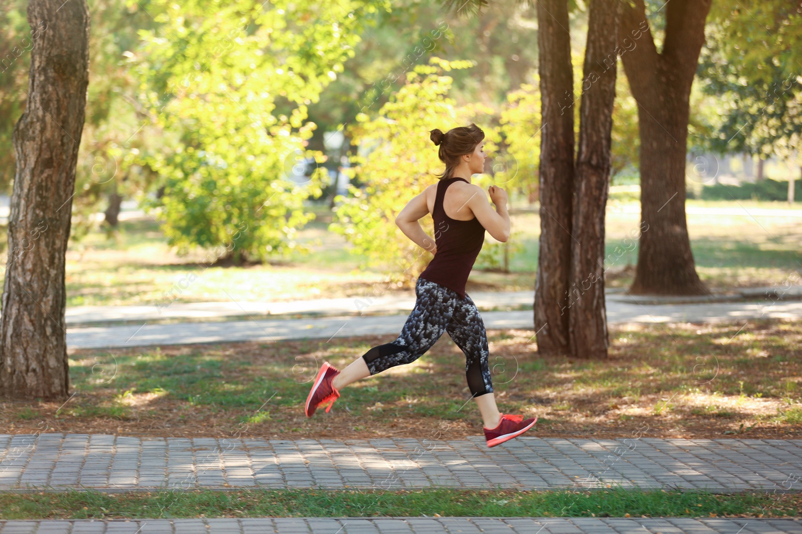 Photo of Young woman running in park on sunny day