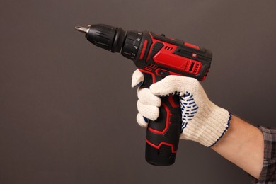 Handyman holding electric screwdriver on brown background, closeup