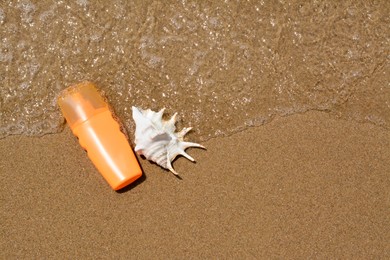Photo of Bottle with sun protection spray and seashell near sea, flat lay. Space for text
