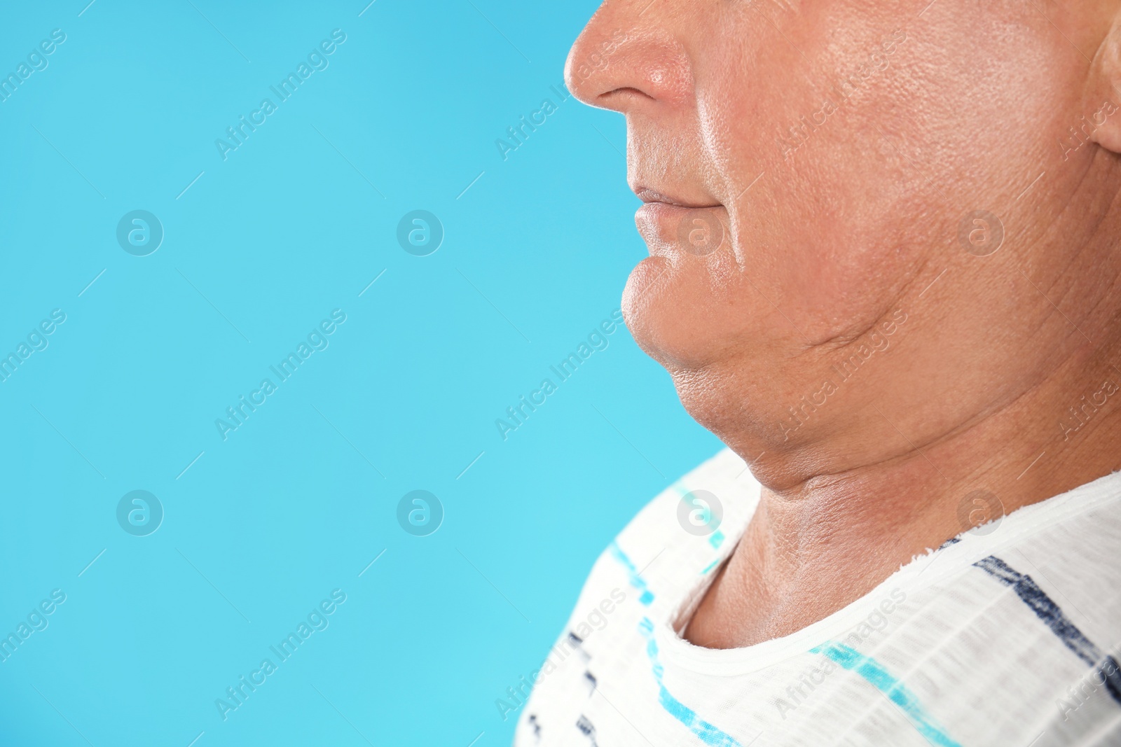 Photo of Mature man with double chin on blue background, closeup. Space for text