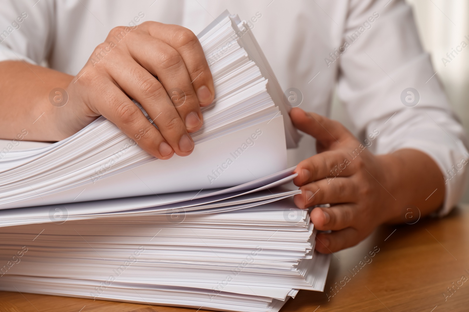 Photo of Man stacking documents at table in office, closeup