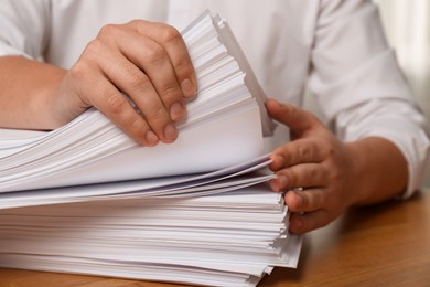 Man stacking documents at table in office, closeup