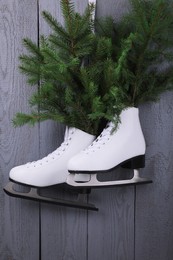 Photo of Pair of ice skates with fir branches hanging on grey wooden wall