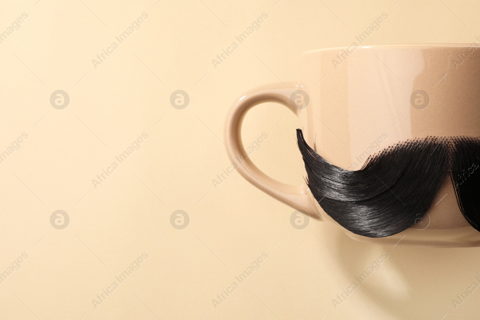 Photo of Artificial moustache and cup on beige background, top view. Space for text